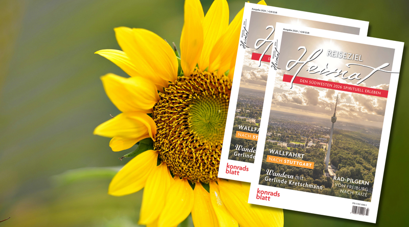 Sonnenblume mit zwei Ausgaben des Magazins „Reiseziel Heimat“ vor unscharfem Naturhintergrund