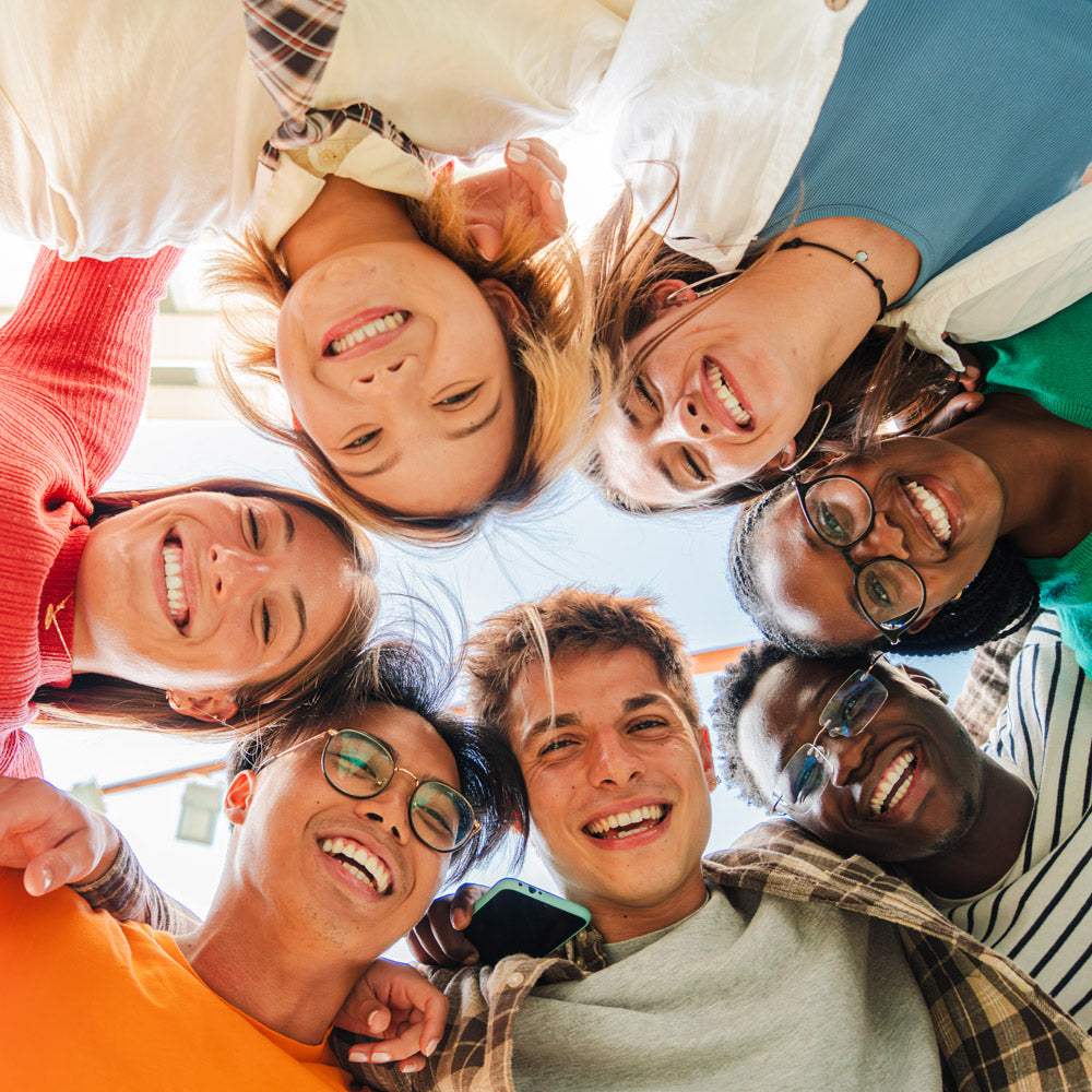Gruppe von jungen Menschen steht im Kreis und schaut nach unten zur Kamera