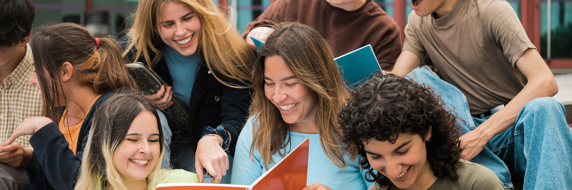 Gruppe von Jugendlichen sitzt zusammen und liest Bücher im Freien